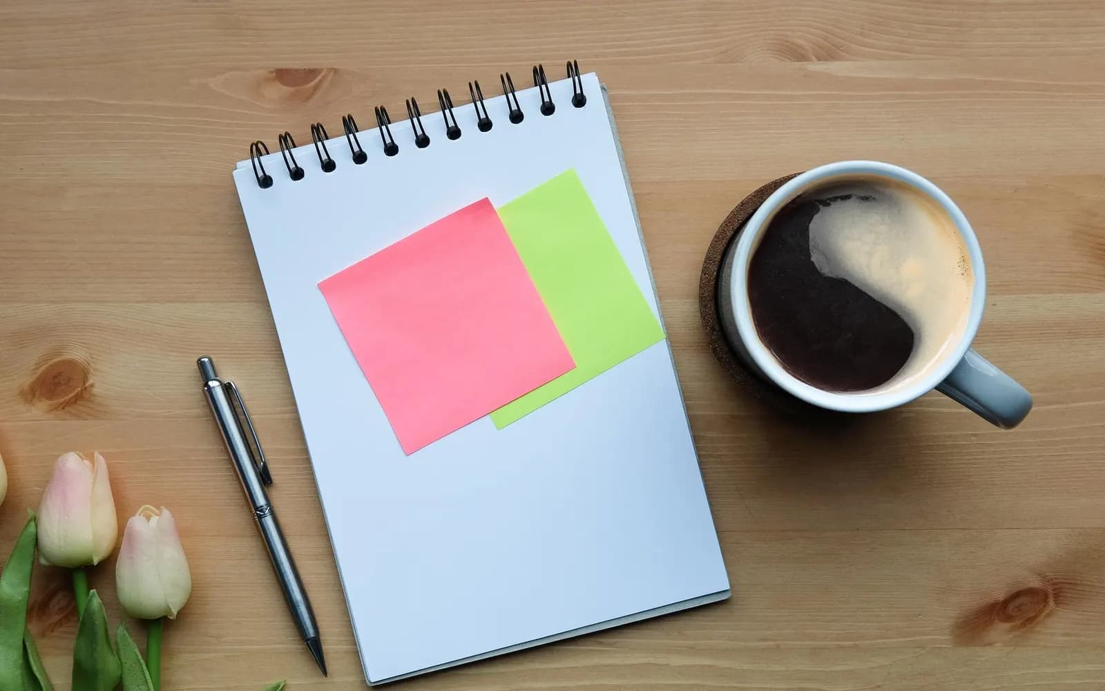 A notebook, pen and coffee on a planning desk.